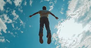 Rapaz jovem de costas dando um salto para o céu azul com algumas nuvens