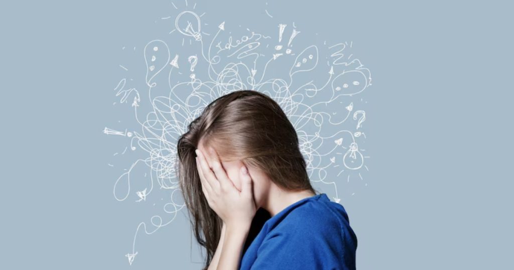 Moça jovem de cabelos longos castanhos de lado com as mãos no rosto com ansiedade.