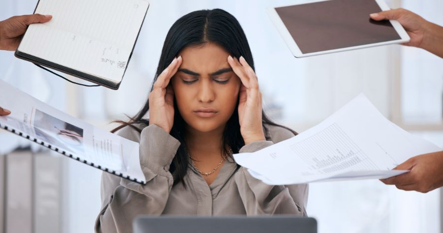 Mulher no trabalho com as mãos na testa sofrendo de saúde mental.