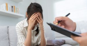 Uma mulher de cabeça baixa cuidando da sua saúde mental em uma consulta com psicólogo.