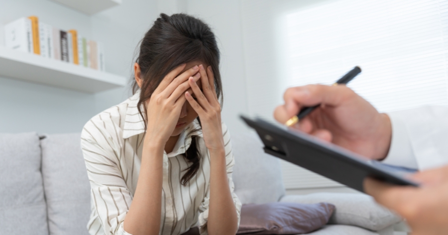 Uma mulher de cabeça baixa cuidando da sua saúde mental em uma consulta com psicólogo.